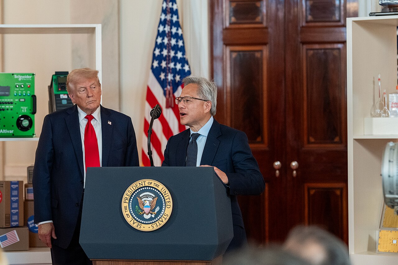 Jensen Huang vorbește la un pupitru al Casei Albe, iar Donald Trump îl ascultă. Fotografie de arhivă din 30 aprilie 2025.